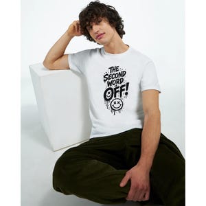 Könnte beinhalten: Ein weißes T-Shirt mit kurzen Ärmeln und einem schwarzen Grafikdruck auf der Brust. Der Text lautet THE SECOND WORD IS OFF! in einer fetten, tropfenden Schriftart, begleitet von zwei Smiley-Symbolen mit X-förmigen Augen und Farbeffekten.