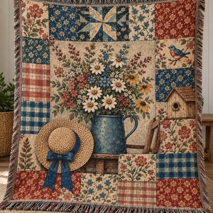 May include: A woven throw blanket featuring a patchwork design with floral, plaid, and gingham patterns in red, blue, and cream. The central panel displays a blue pitcher filled with daisies, a straw hat with a blue ribbon, and a birdhouse.