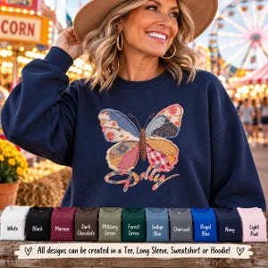 May include: A navy blue sweatshirt featuring a large, central butterfly graphic composed of various colorful, patterned fabric patches. Below the butterfly, the word Dolly is written in a cursive, multi-colored script font.