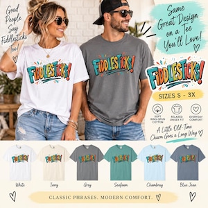 May include: A collection of short-sleeve t-shirts in white, ivory, grey, seafoam, chambray, and blue jean colors. Each shirt features the text "FIDDLESTICKS!" in a colorful, bold font. The shirts are available in sizes S through 3X.
