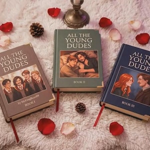 May include: Three hardcover books titled All The Young Dudes, labeled Book I, Book II, and Book III. The books are brown, green, and dark blue with gold corner accents, red ribbon bookmarks, and illustrated covers featuring various characters.