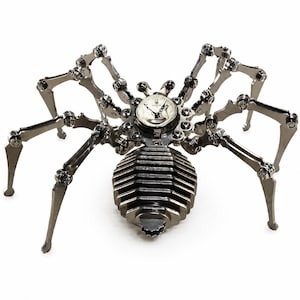Könnte beinhalten: Eine metallene Spinnenskulptur aus dunkelgrauen Stahlkomponenten mit acht beweglichen Beinen und einem segmentierten Hinterleib. Der zentrale Körper enthält ein rundes analoges Zifferblatt mit dem aufgedruckten Schriftzug "CANTON".