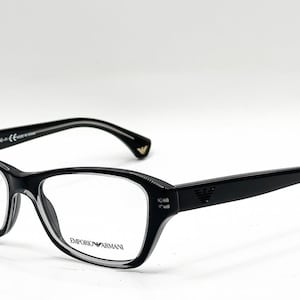 Puede incluir: Gafas Emporio Armani negras con acabado brillante, con borde inferior transparente, el logotipo de Emporio Armani en la lente derecha y el emblema del águila en la patilla. La patilla interior incluye texto de la marca y marcas CE.