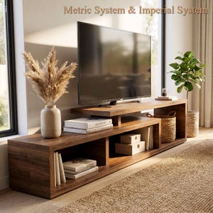 Può includere: Un mobile porta TV lungo e basso in legno con finitura marrone scuro, caratterizzato da un design a scaffali aperti. L'unità ospita un televisore a schermo piatto, un vaso in ceramica beige con erba della pampa secca, libri e due scatole in legno.