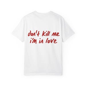 Può includere: Una t-shirt bianca a maniche corte con la scritta rossa "don't kill me i'm in love" stampata in stile manoscritto al centro del petto. Il capo presenta un girocollo standard e una parte posteriore liscia di colore bianco tinta unita.