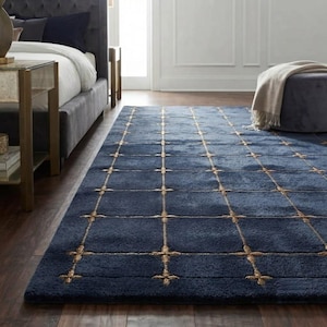 May include: A rectangular area rug featuring a deep navy blue pile with a repeating grid pattern formed by thin, metallic gold lines. The intersections of the grid are accented with small, cross-shaped gold embroidery details across the surface.