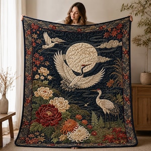 May include: A rectangular quilt featuring a dark blue background with a large cream-colored moon, three white cranes, and vibrant red, orange, and cream-colored floral patterns including peonies and chrysanthemums with green foliage.