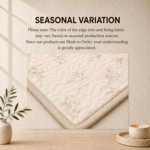 K&ouml;nnte beinhalten: Ein cremefarbener, gesteppter Stoff mit hellbraunem Blumenmuster und einem einfarbigen Rand. Der Text lautet: SEASONAL VARIATION. Bitte beachten Sie: Die Farbe der Kanten und des Futters kann je nach saisonaler Produktion variieren.