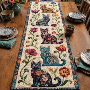May include: A rectangular quilted table runner featuring a cream-colored background with five distinct cats in various colors, including orange, blue, purple, and dark blue, each decorated with intricate floral patterns and surrounded by colorful flowers.