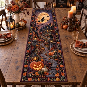 May include: A rectangular table runner featuring a detailed Halloween scene with a full moon, a witch on a broomstick, a haunted house, a black cat, and a glowing jack-o'-lantern on a stone path surrounded by autumn leaves and orange pumpkins.