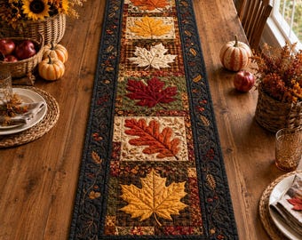 May include: A rectangular quilted table runner featuring a central row of six square blocks, each displaying a different autumn leaf in shades of orange, yellow, cream, red, and brown, bordered by a dark fabric with embroidered leaf motifs.