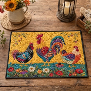 May include: A rectangular quilted fabric mat featuring a central scene of three colorful chickens standing in a field of flowers. The background is a golden yellow with swirling patterns, while the foreground shows green grass and various floral motifs.