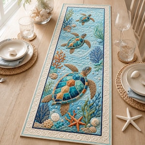 May include: A rectangular quilted table runner featuring a vibrant underwater scene with three sea turtles, orange and blue coral, starfish, and seashells. The design is set against a light blue water background with a cream-colored border.