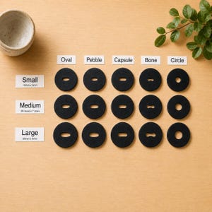 May include: A grid of black buttons arranged in rows labeled Small 16mm x 6mm, Medium 20.5mm x 7.5mm, and Large 25mm x 9mm. The columns are labeled Oval, Pebble, Capsule, Bone, and Circle, indicating the specific shape of the center cutout in each button.