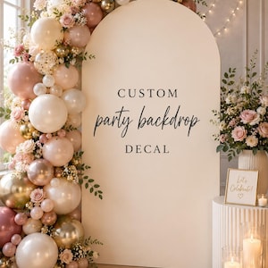 Op de afbeelding: Een grote boogvormige feestachtergrond met een aangepaste sticker met de tekst CUSTOM party backdrop DECAL. De boog is versierd met een dichte ballonslinger in tinten crème, poederroze en metallic goud, geaccentueerd met kleine roze rozen.