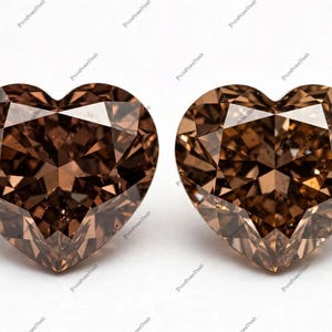 Pode incluir: Duas pedras preciosas soltas em forma de coração com uma cor castanha profunda e corte facetado. Cada pedra apresenta uma silhueta de coração simétrica com múltiplas facetas triangulares que refletem a luz na superfície castanha.