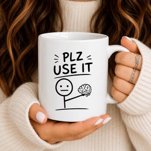 Peut inclure: Un mug en céramique blanche orné d'un dessin noir représentant un personnage en bâtonnets tenant un cerveau. Au-dessus du personnage, le texte "PLZ USE IT" est inscrit dans une police sans empattement. Le motif est centré sur le mug.
