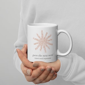 May include: A white ceramic mug featuring a star-shaped graphic composed of small, light brown text. Below the graphic, the text reads "guess the next word" in a larger font, followed by the smaller text "repeat until impressive" below it.