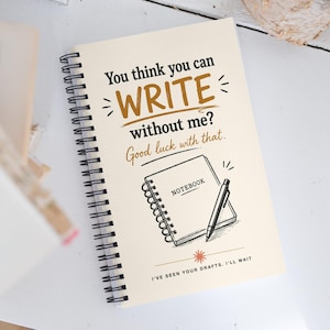 May include: A spiral-bound notebook with a cream cover featuring black and brown text that reads: You think you can WRITE without me? Good luck with that. It includes a graphic of a notebook and pen, with the text: I'VE SEEN YOUR DRAFTS. I'LL WAIT.