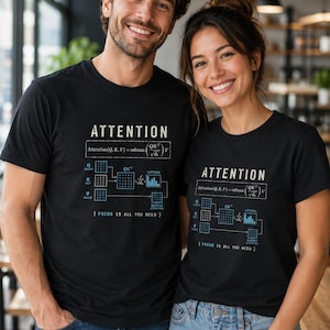 Könnte beinhalten: Ein schwarzes T-Shirt mit einem weißen und blauen Grafikdruck der Attention-Mechanismus-Formel, einschließlich des Textes ATTENTION, der mathematischen Gleichung, eines Diagramms der Q-, K- und V-Matrizen und des Satzes FOCUS IS ALL YOU NEED.