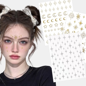 Pode incluir: Três folhas de autocolantes temporários para o rosto em ouro e prata metalizados com motivos celestiais, incluindo sóis, luas e estrelas. Os desenhos são aplicados na testa e nas bochechas, exibindo vários tamanhos de sóis radiantes, luas crescentes e estrelas de quatro pontas.