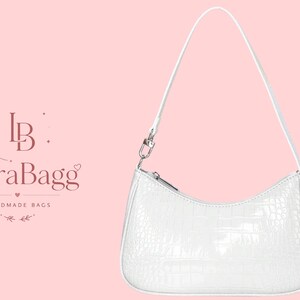 May include: A white shoulder bag with a textured crocodile-embossed pattern, featuring a single thin strap, a curved top zipper closure, and silver-toned hardware. To the left, the text reads LB LioraBagg HANDMADE BAGS with floral accents.