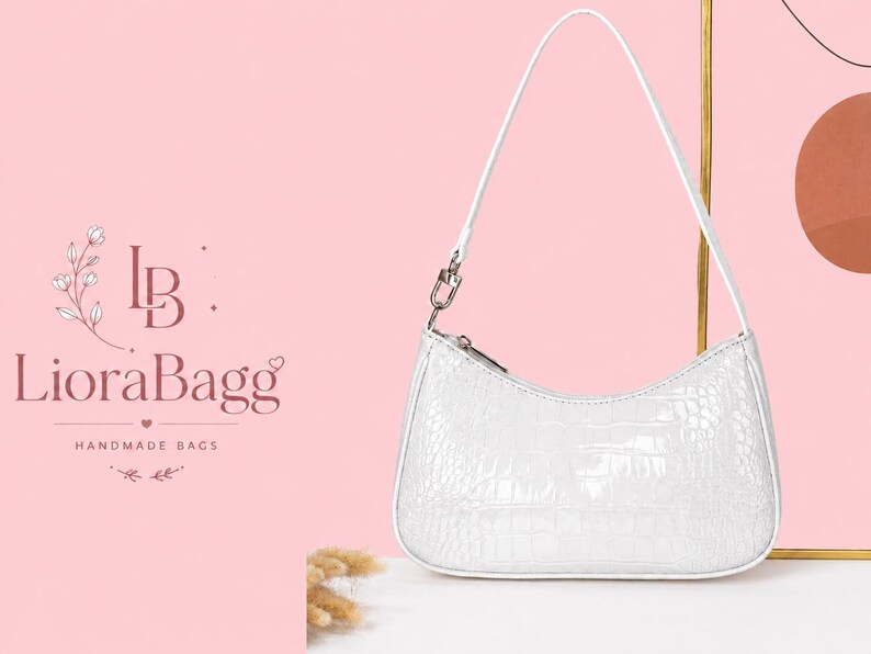 May include: A white shoulder bag with a glossy crocodile skin texture, featuring a single thin strap attached with silver-toned metal hardware and a top zipper closure. The bag has a curved, crescent-shaped silhouette and a smooth white trim.