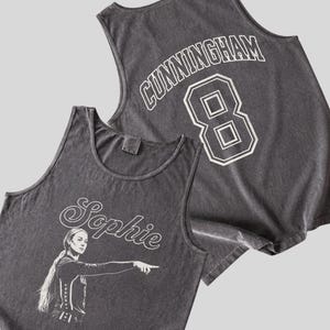 May include: A charcoal gray sleeveless tank top featuring a white graphic of a basketball player pointing, with the name Sophie in script above. The back displays the name CUNNINGHAM and the number 8 in a bold white collegiate font style.