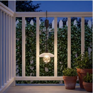 May include: A hanging outdoor pendant light featuring a clear, textured, dome-shaped shade and a spherical bulb containing warm, glowing string lights. The fixture is suspended by a black cord and a hook, emitting a soft, ambient illumination.