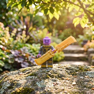 Könnte beinhalten: Eine violetthäutige Minifigur mit detailliertem grau-goldenen Torso-Aufdruck, die ein großes, doppelschneidiges goldenes Schwert hält. Die Figur hat einen markanten Gesichtsausdruck mit dunklen Markierungen und steht aufrecht, was die komplexen Kunststoffdetails zeigt.