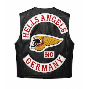 Può includere: Un gilet in pelle nera con toppe ricamate sul retro. La toppa superiore riporta la scritta HELLS ANGELS in rosso su sfondo bianco. Una toppa centrale raffigura un logo con teschio alato in giallo, rosso e bianco. La toppa inferiore riporta GERMANY.
