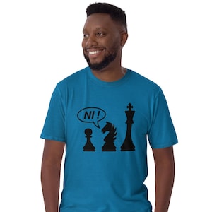 May include: A teal short-sleeved t-shirt featuring a black graphic of a chess pawn, a knight, and a king. The pawn has a speech bubble above it containing the text NI!. The shirt has a crew neckline and a standard fit, providing a casual look.
