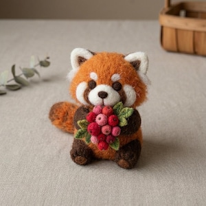 May include: A needle-felted red panda figurine with orange and white fur, dark brown limbs, and a bushy tail. The creature is holding a cluster of small, round red and pink berries with green felt leaves tucked against its chest.