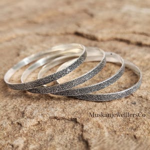 May include: A set of four silver-toned bangles featuring a textured, granular surface finish. The circular bracelets are arranged in a slightly overlapping stack. The text MuskanjewelllersCo is visible in the lower right corner of the image.