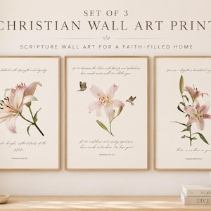 May include: A set of three rectangular wall art prints featuring light pink lily illustrations and black cursive scripture text on a cream background. The text includes SET OF 3 CHRISTIAN WALL ART PRINTS and SCRIPTURE WALL ART FOR A FAITH-FILLED HOME.