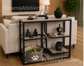 May include: A rectangular console table with a black metal frame and light wood-toned shelves. The unit features multiple levels for storage, including a bottom shelf holding a grey fabric bin with a white paw print design. Text reads ElvarraAtelier.