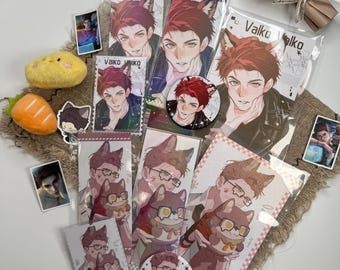 May include: A collection of anime-style merchandise featuring a character with red hair and animal ears, including rectangular prints, circular buttons, and small stickers labeled Valko, alongside a yellow plush chick and an orange plush carrot.