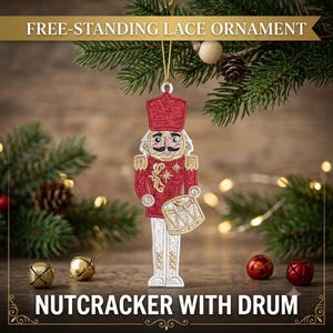 May include: A free-standing lace ornament shaped like a nutcracker soldier wearing a red uniform with gold embroidery and holding a drum. The ornament features a tall hat, white trousers, and a gold hanging string, with text reading FREE-STANDING LACE ORNAMENT and NUTCRACKER WITH DRUM.