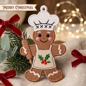 Peut inclure: Une décoration brodée en forme de bonhomme en pain d'épices portant une toque de chef blanche avec des détails en X noirs et un tablier blanc orné de houx vert et de baies rouges. Le personnage tient un rouleau à pâtisserie marron.