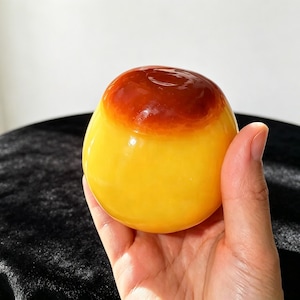Könnte beinhalten: Ein glattes, abgerundetes Objekt mit glänzender Oberfläche, das eine leuchtend gelbe Basis besitzt, die in eine tief dunkelrotbraune Kappe übergeht. Das Objekt hat eine bauchige, kugelförmige Gestalt mit einer polierten Oberfläche, die Licht reflektiert.