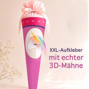 Op de afbeelding: Een roze kegelvormige geschenkverpakking met een eenhoornillustratie met een regenboogkleurige 3D-manen, afgewerkt met een lichtroze satijnen strik. De tekst XXL-Aufkleber mit echter 3D-Mähne staat in donkerpaars en roze afgedrukt.