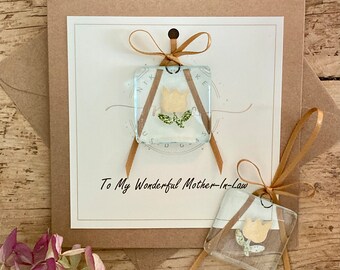 May include: A card with a brown envelope and a small glass square with a pressed flower inside. The card says "To My Wonderful Mother-In-Law".