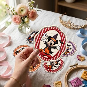 May include: A circular embroidered patch featuring Mickey Mouse dressed in a Halloween costume with a witch hat, a ghost, and a pumpkin. The patch has a red and white striped border. Other similar patches are visible in the background.