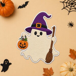 Peut inclure: Un écusson brodé représentant un fantôme crème portant un chapeau de sorcière violet avec une bande noire et une boucle orange. Le fantôme tient une petite citrouille d'Halloween orange dans une main et un balai en bois marron dans l'autre.