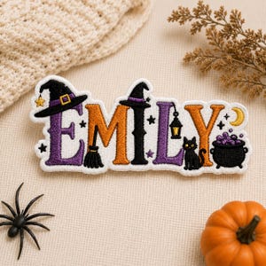 Może przedstawiać: Haftowana naszywka z imieniem EMILY w stylu Halloween. Litery są fioletowe, pomarańczowe i czarne, ozdobione kapeluszem czarownicy, miotłą, latarnią, czarnym kotem, kociołkiem z fioletowymi bąbelkami, gwiazdkami i żółtym półksiężycem.