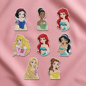 Op de afbeelding: Een verzameling van acht gestanste stickers met geïllustreerde tekenfilmfiguren. De figuren hebben zwart, rood, blond en bruin haar en dragen diverse kleurrijke outfits zoals blauwe, groene, roze en gele jurken.