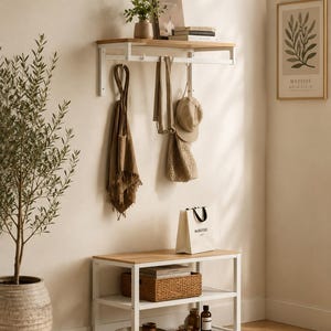 May include: A wall-mounted coat rack with a light wood shelf and white metal frame, featuring hooks holding a brown scarf, a beige cap, and a woven bag. Below, a matching white metal shoe bench with a light wood top and two shelves.