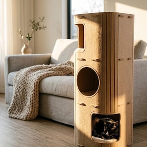Peut inclure: Une tour à chat haute de couleur beige, composée de panneaux modulaires à rainures verticales. Elle comprend un perchoir ouvert en haut, une ouverture circulaire au milieu et une niche carrée en bas où un chat noir se repose sur un coussin blanc.