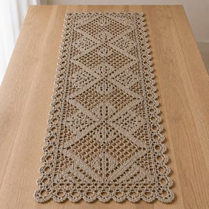 May include: A rectangular beige crochet table runner featuring a repeating geometric pattern of diamonds and openwork mesh. The runner has a scalloped border with circular motifs along the entire edge, showcasing intricate needlework detail.