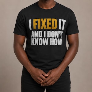 Puede incluir: Una camiseta negra de manga corta y cuello redondo con el texto I FIXED IT AND I DON'T KNOW HOW impreso en una tipografía desgastada. La palabra FIXED aparece en un color amarillo intenso, mientras que el resto es de color blanco.